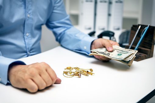 Man buying gold jewellry, pawn shop and us dollar banknotes